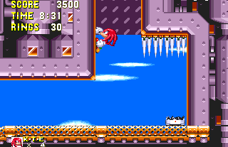 Eventually, you'll reach a dead end, with a ten ring item box and spikes on the ceiling. There's a shaft leading upwards though, and Knuckles can make a head start by climbing up here. Sonic will have to wait for the platform to carry him, though be very careful that it doesn't force you into the spikes as it moves to the right.